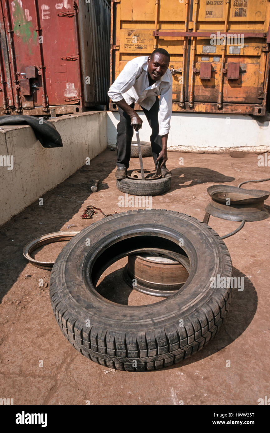 Man repairs a flat car tire at a local repair service, Moshi, Tanzania Stock Photo