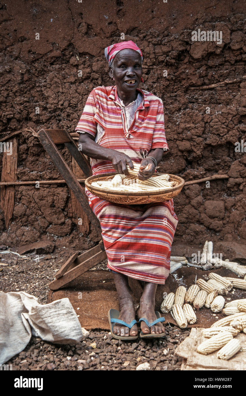 An old woman removes kernels from a maize cob, Himo, Kilimanjaro Region, Tanzania Stock Photo