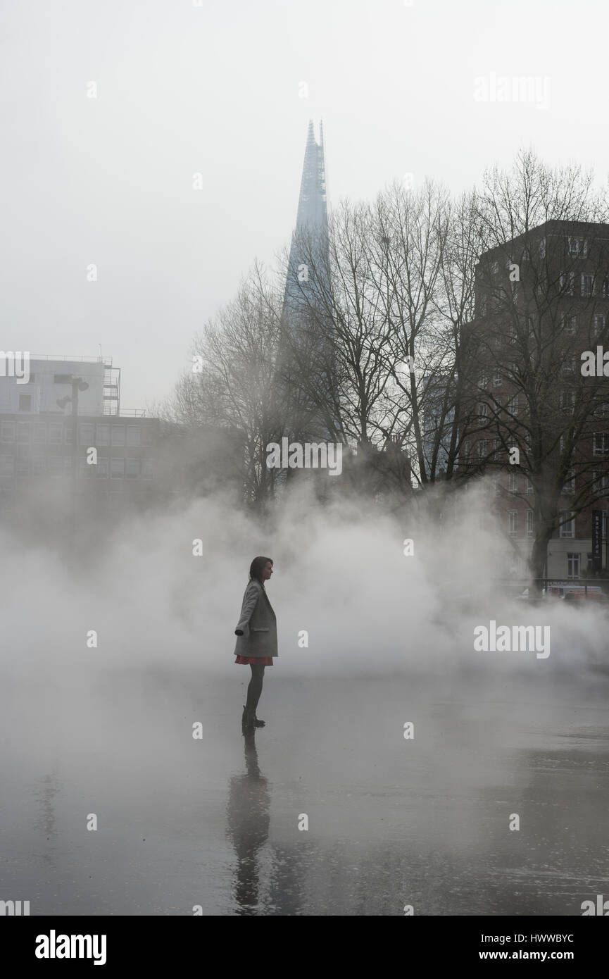Tate Modern, London, UK. 23rd March 2017. BMW Tate Live exhibition, Ten Days Six Nights. Fujiko Nakaya fog sculpture debuts outside Tate Modern’s Switch House, posed with a member of gallery staff. Credit: Malcolm Park editorial/Alamy Live News. Stock Photo