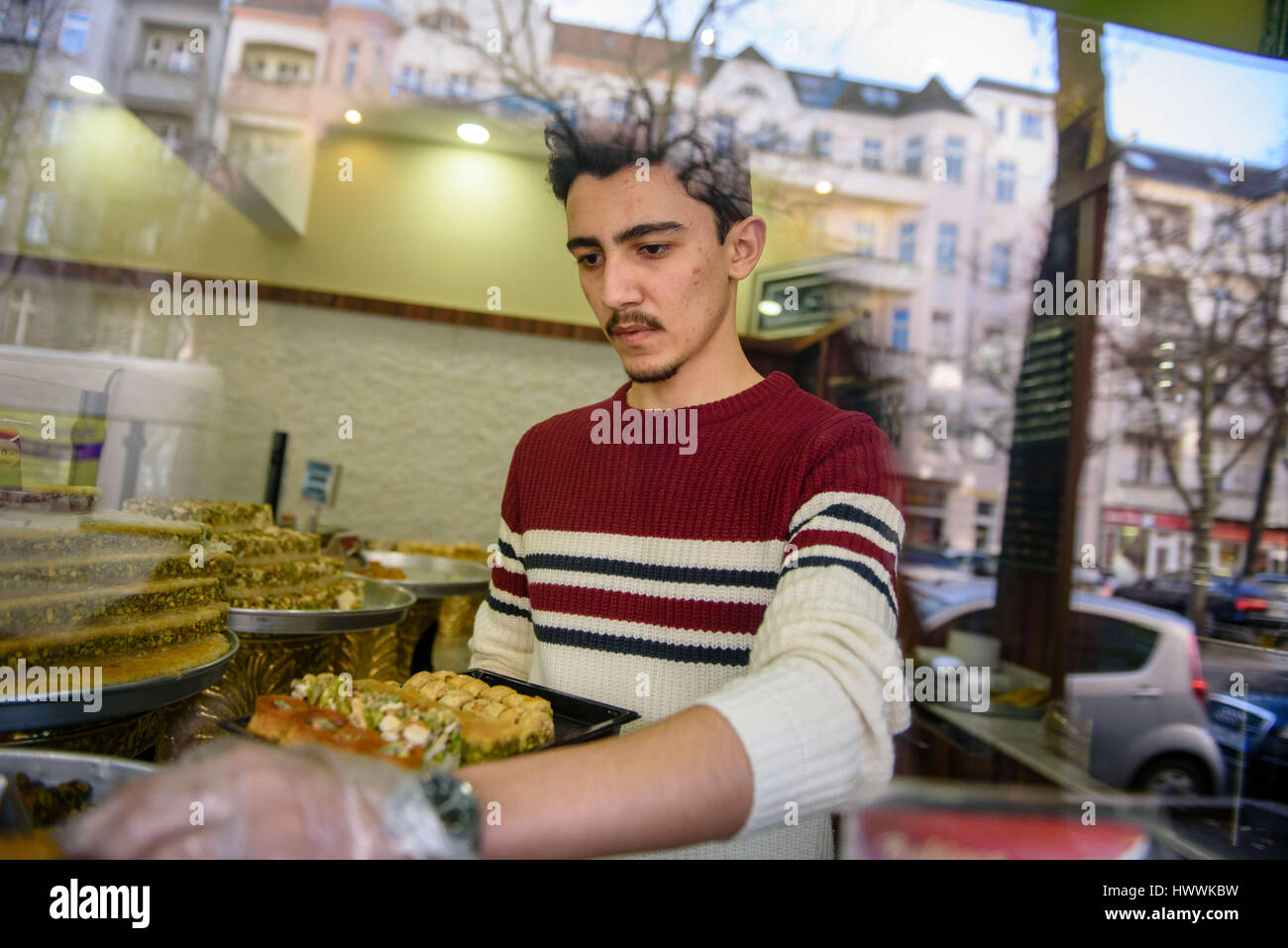 Berlin, Germany. 15th Mar, 2017. Sulaiman al-Sakka, employee and son of the family, puts together a present box with sweets at the confectionary Damaskus in Berlin, Germany, 15 March 2017. The al-Sakka family opened the Syrian confectionary in the district of Neukoelln in Berlin, three years after arriving in Germany. Photo: Gregor Fischer/dpa/Alamy Live News Stock Photo