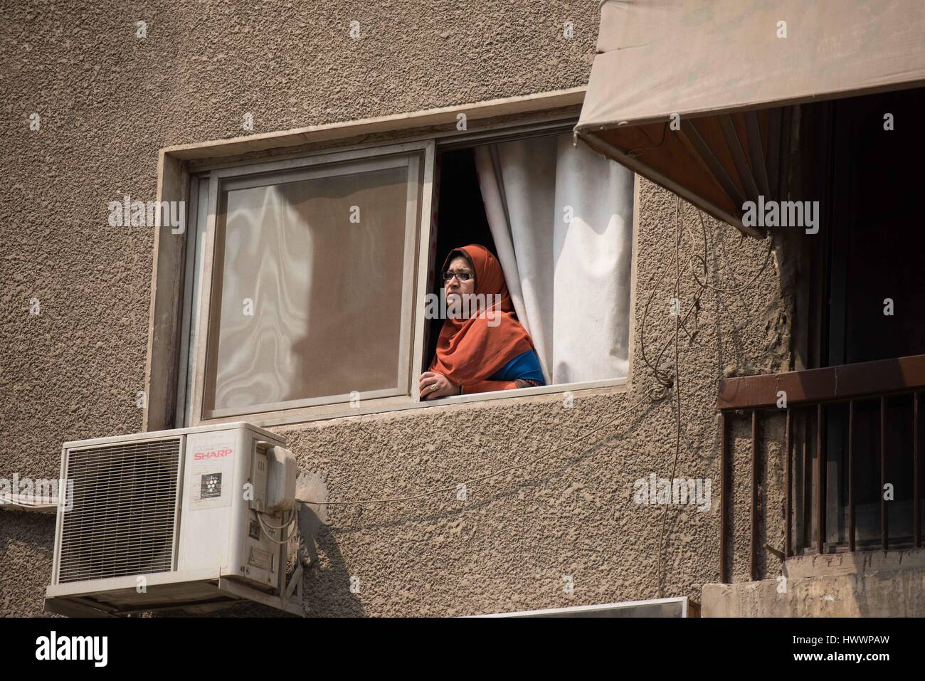 Cairo, Egypt. 24th Mar, 2017. A woman looks out of the window near the explosion site at Maadi district in Cairo, Egypt, March 24, 2017. One person was killed and four others wounded on Friday when an explosive device went off in a garden in Maadi district southeastern the capital Cairo, the interior ministry said in a statement. Credit: Meng Tao/Xinhua/Alamy Live News Stock Photo