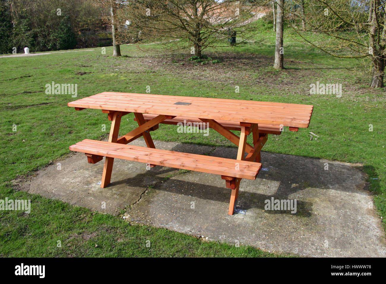 Wooden picnic table on concrete base in a grass picnic site with a