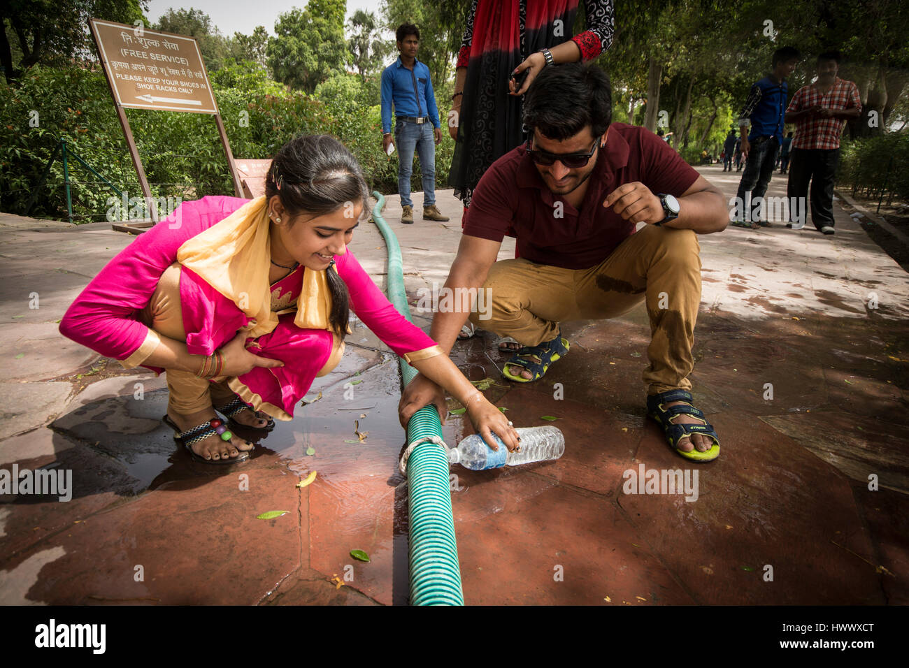 People are collecting water at a broken garden hose at one of the most famous tourist attraction points in India, at the Tadsch Mahal. Stock Photo