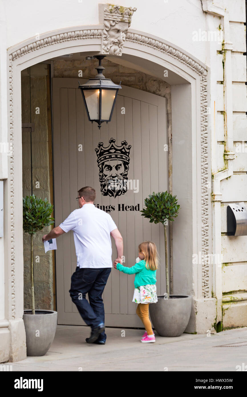 Cirencester - Man and young girl rushing into the Kings Head hotel at Cirencester, Gloucestershire in March Stock Photo