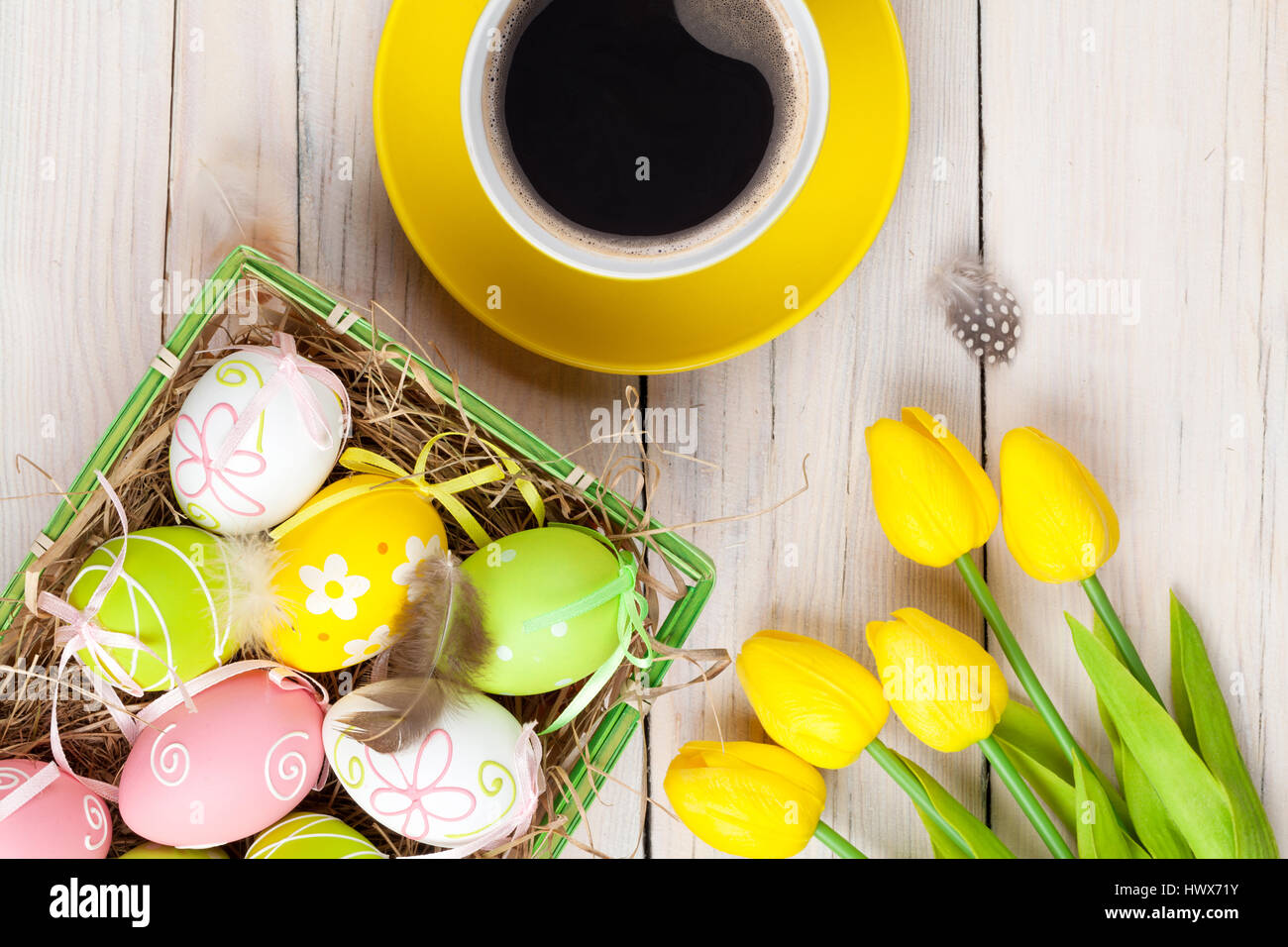 Easter background with colorful eggs and yellow tulips over white wood ...
