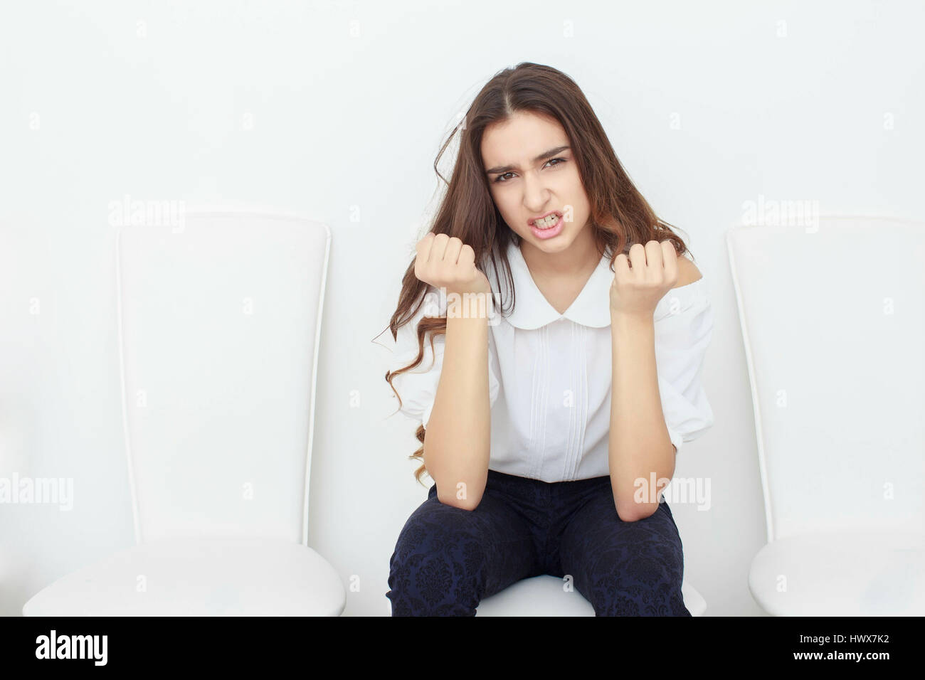 A beautiful girl is sitting on chair and angry Stock Photo