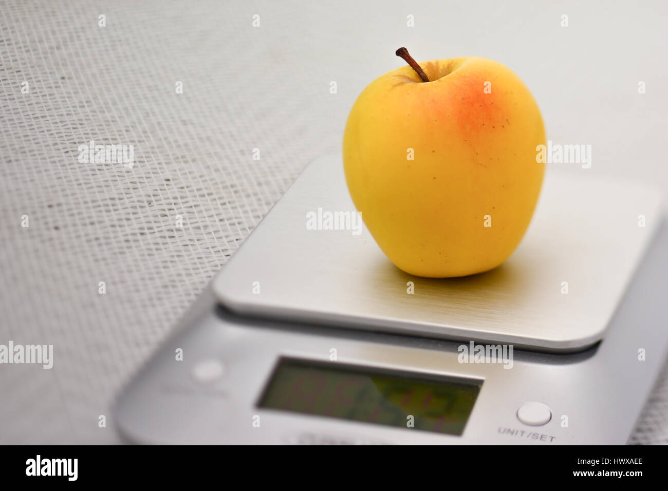 https://c8.alamy.com/comp/HWXAEE/a-single-golden-apple-on-a-stainless-steel-kitchen-scale-HWXAEE.jpg