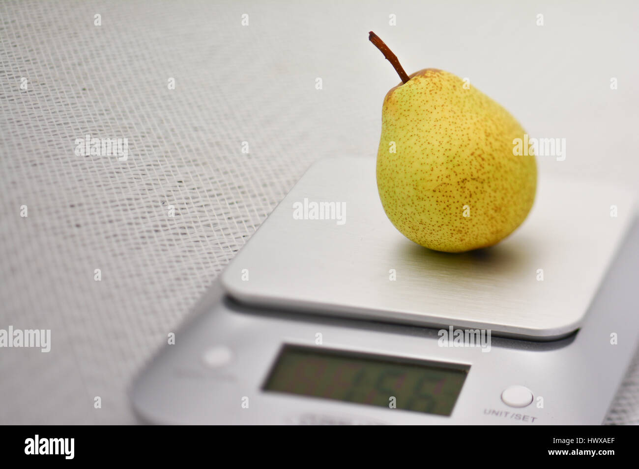 a single williams pear on a silver kitchen scale Stock Photo