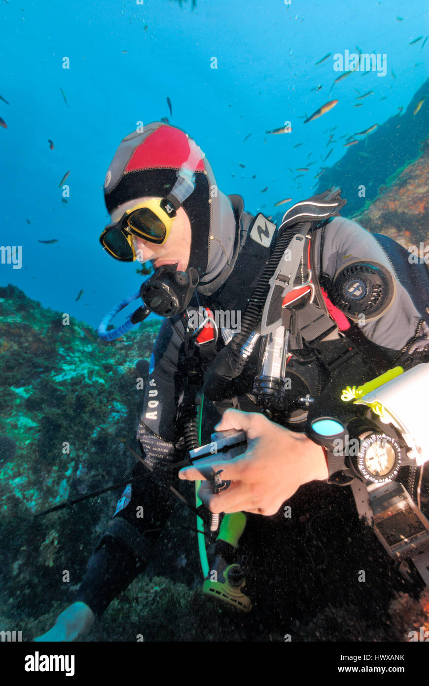 Scuba diver underwater looking at equipment on seabed Stock Photo