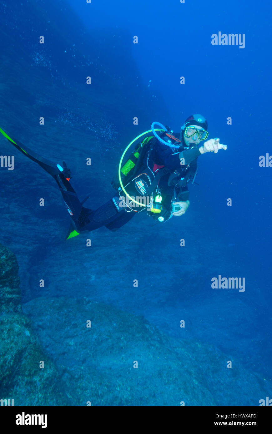 Scuba diver hanging midwater above rocky seabed Stock Photo