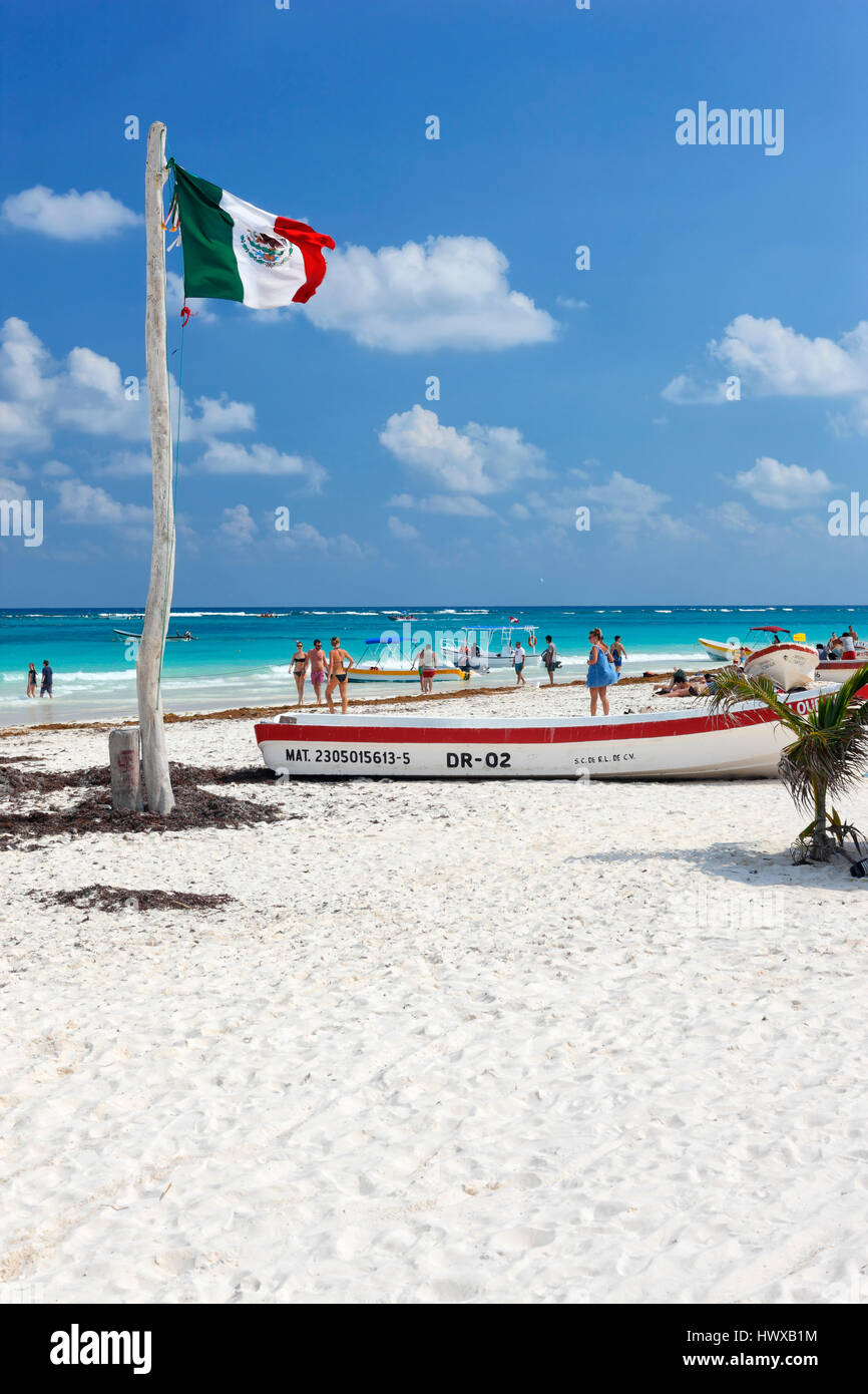 Flag and fishing boats on sand beach in Tulum, Mexico Stock Photo