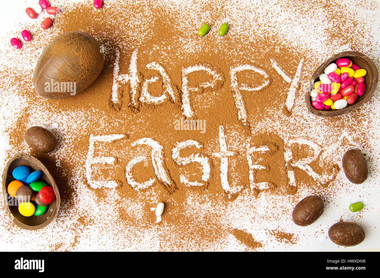 Happy Easter written in cacao powder with chocolate eggs Stock Photo