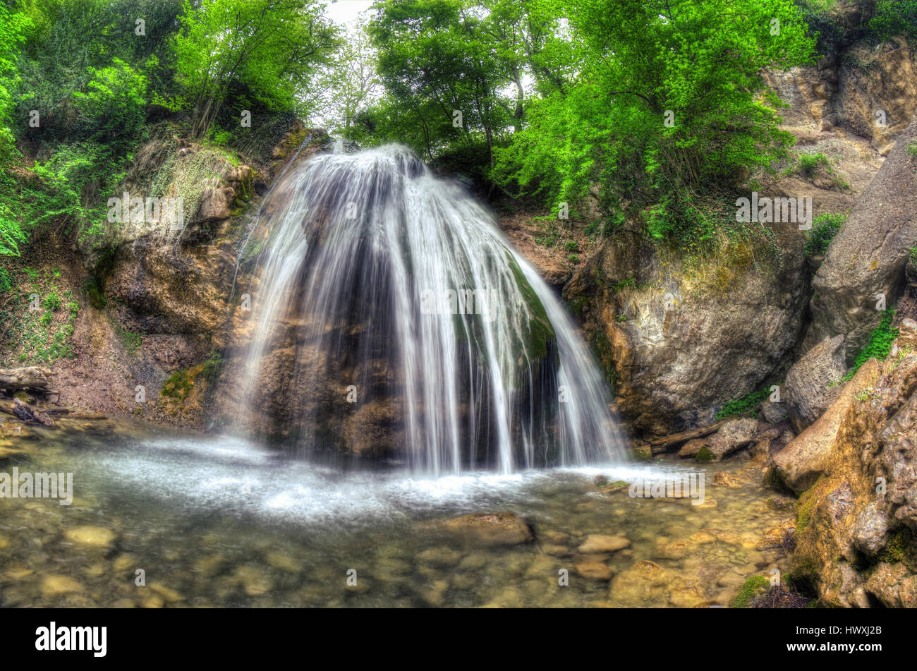 Beautiful waterfall on the mountain river with green trees. Spring ...