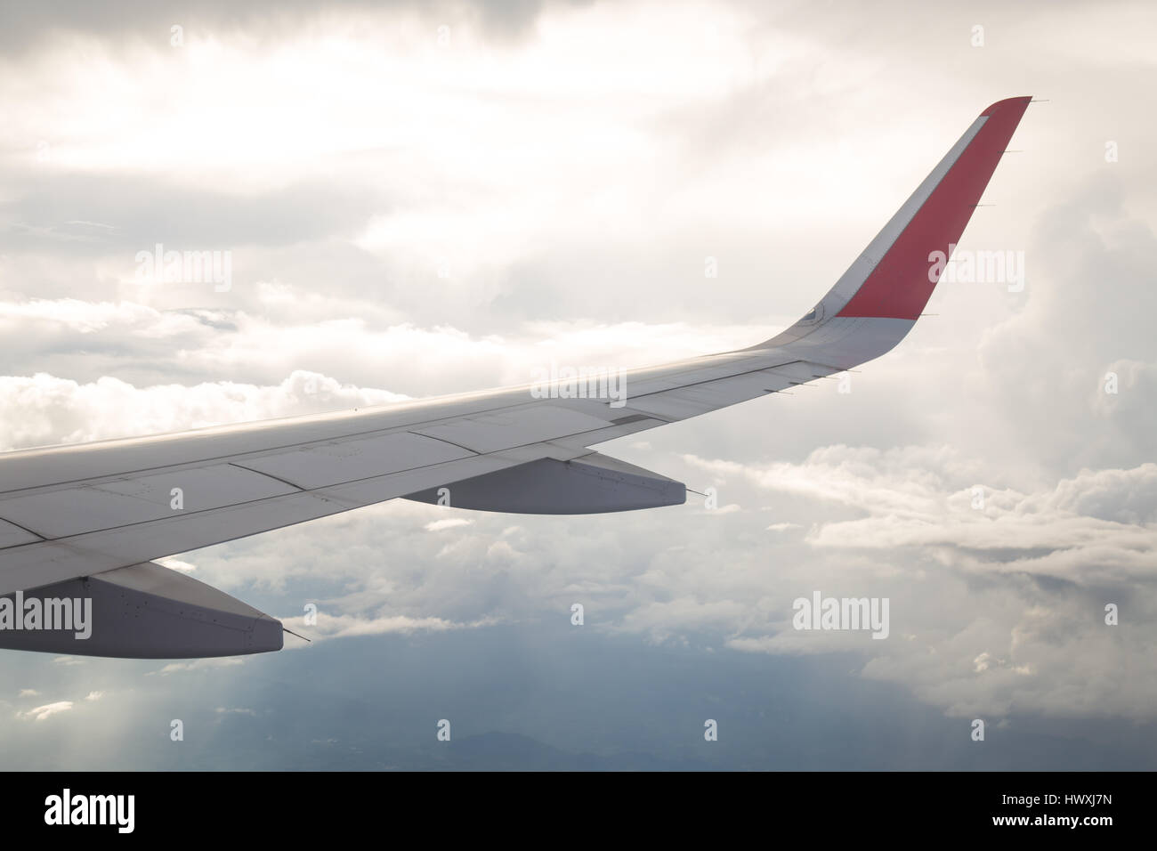 Wing of an airplane flying above the blue sky and clouds Stock Photo ...