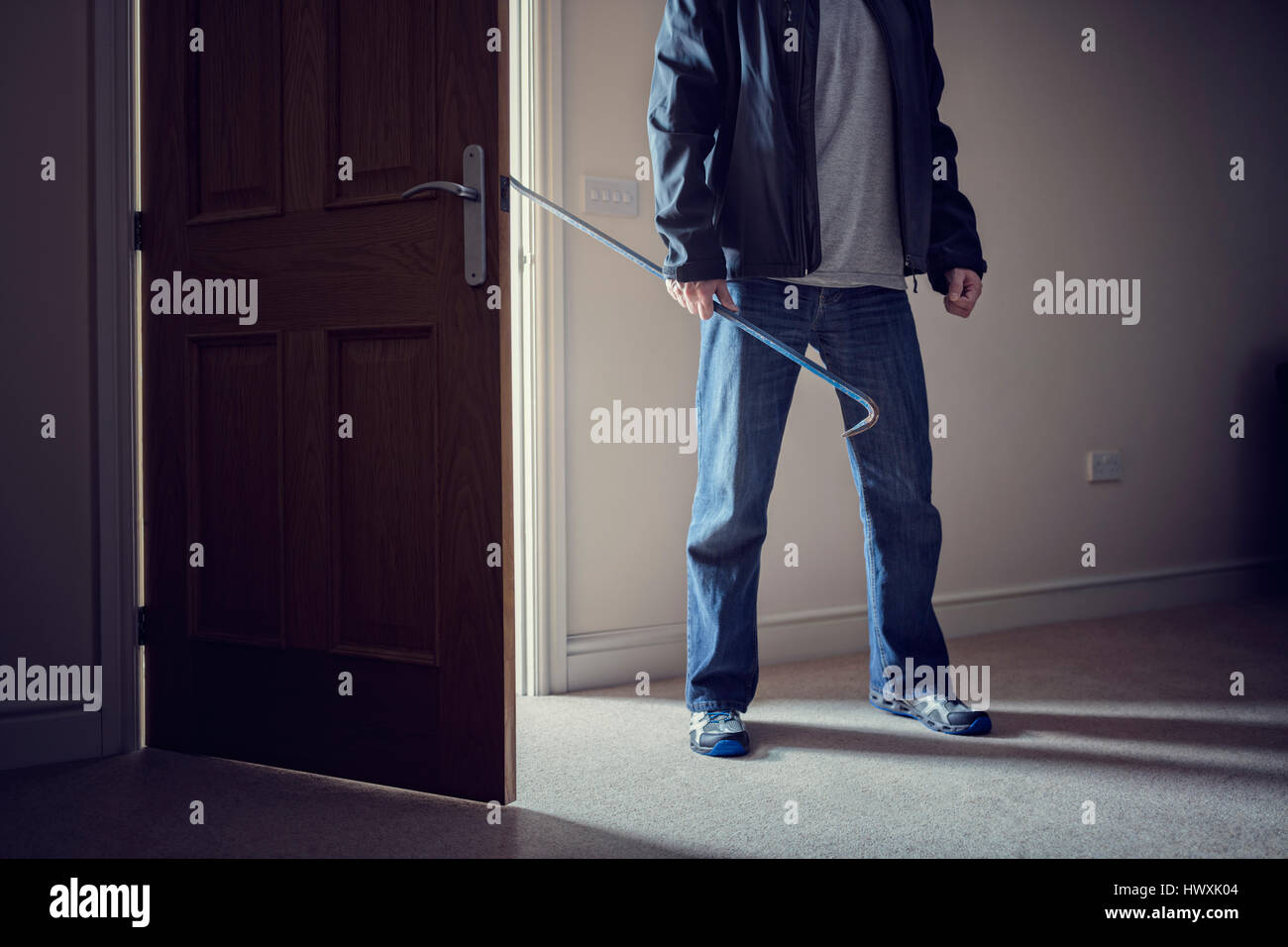 Burglar committing a burglary crime in a house with a crowbar Stock Photo