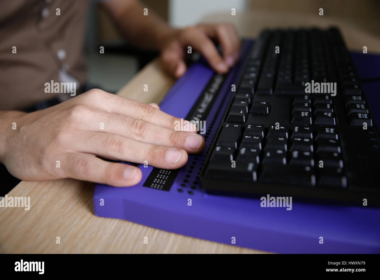 Blind person using computer with braille computer display and a computer keyboard. Blindness aid, visual impairment, independent life concept. Stock Photo