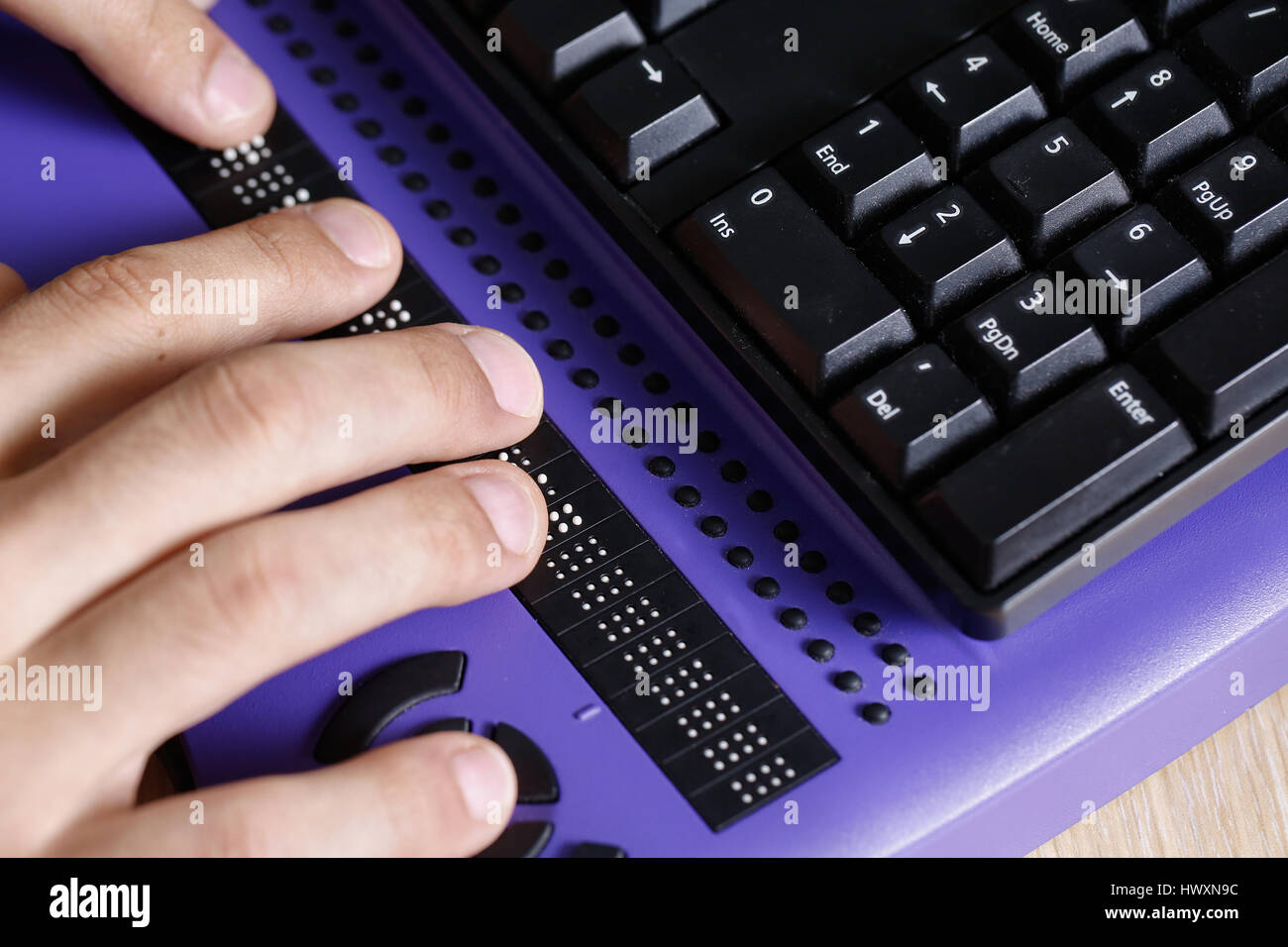 Blind person using computer with braille computer display and a computer keyboard. Blindness aid, visual impairment, independent life concept. Stock Photo