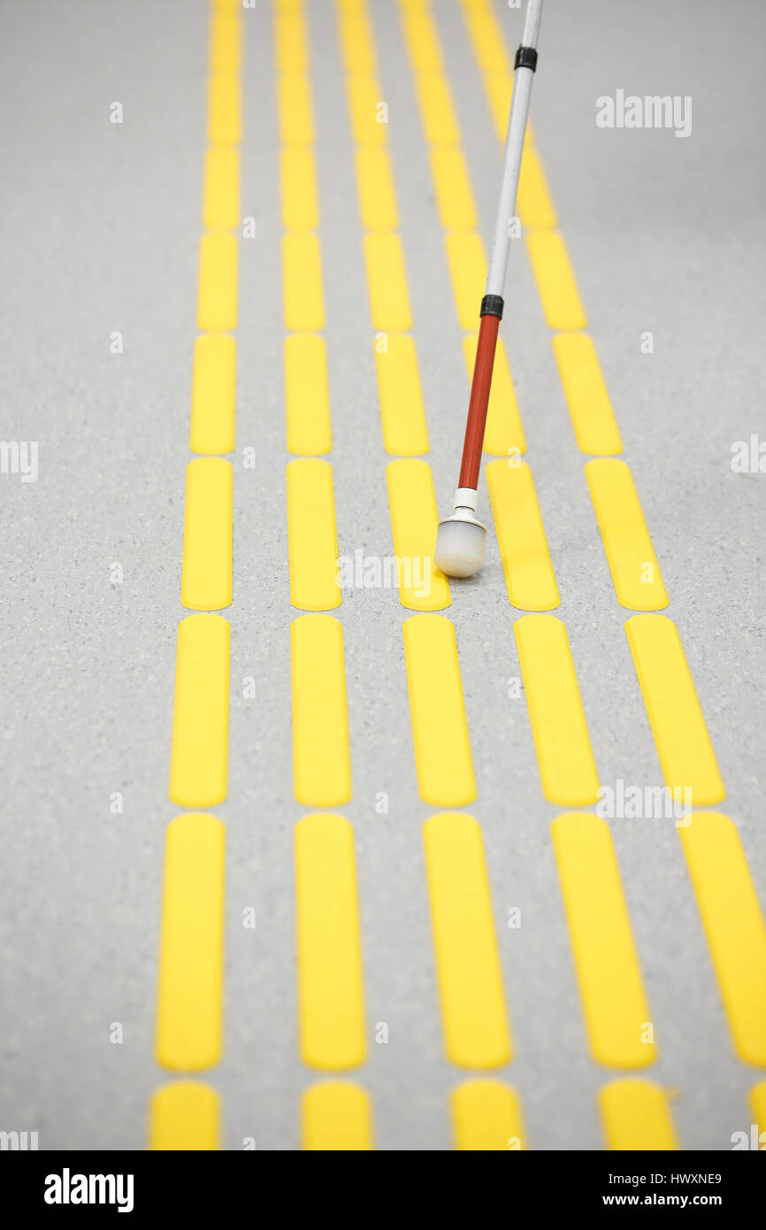 Blind pedestrian walking and detecting markings on tactile paving with textured ground surface indicators for blind and visually impaired. Blindness a Stock Photo