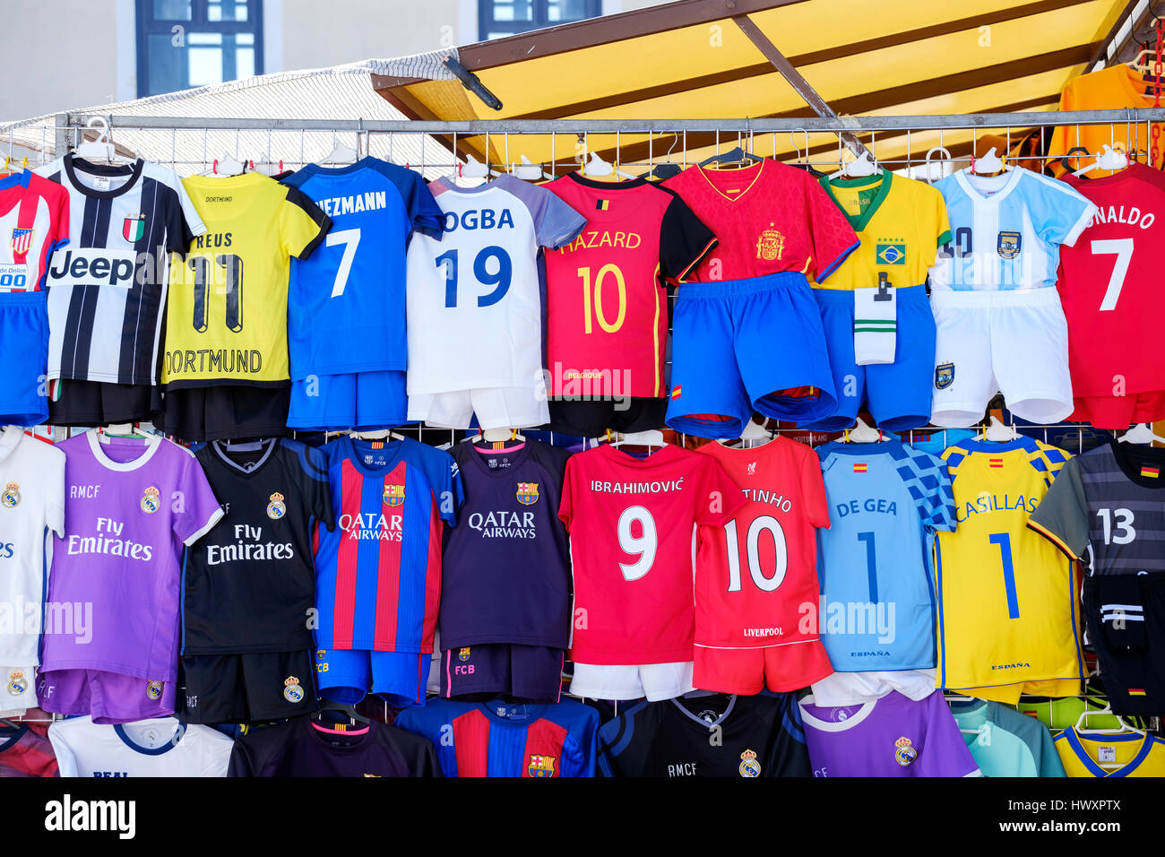 An outdoor market stall displaying an assorted range of childrens replica football shirts with assorted top players names across the shirt back Stock Photo