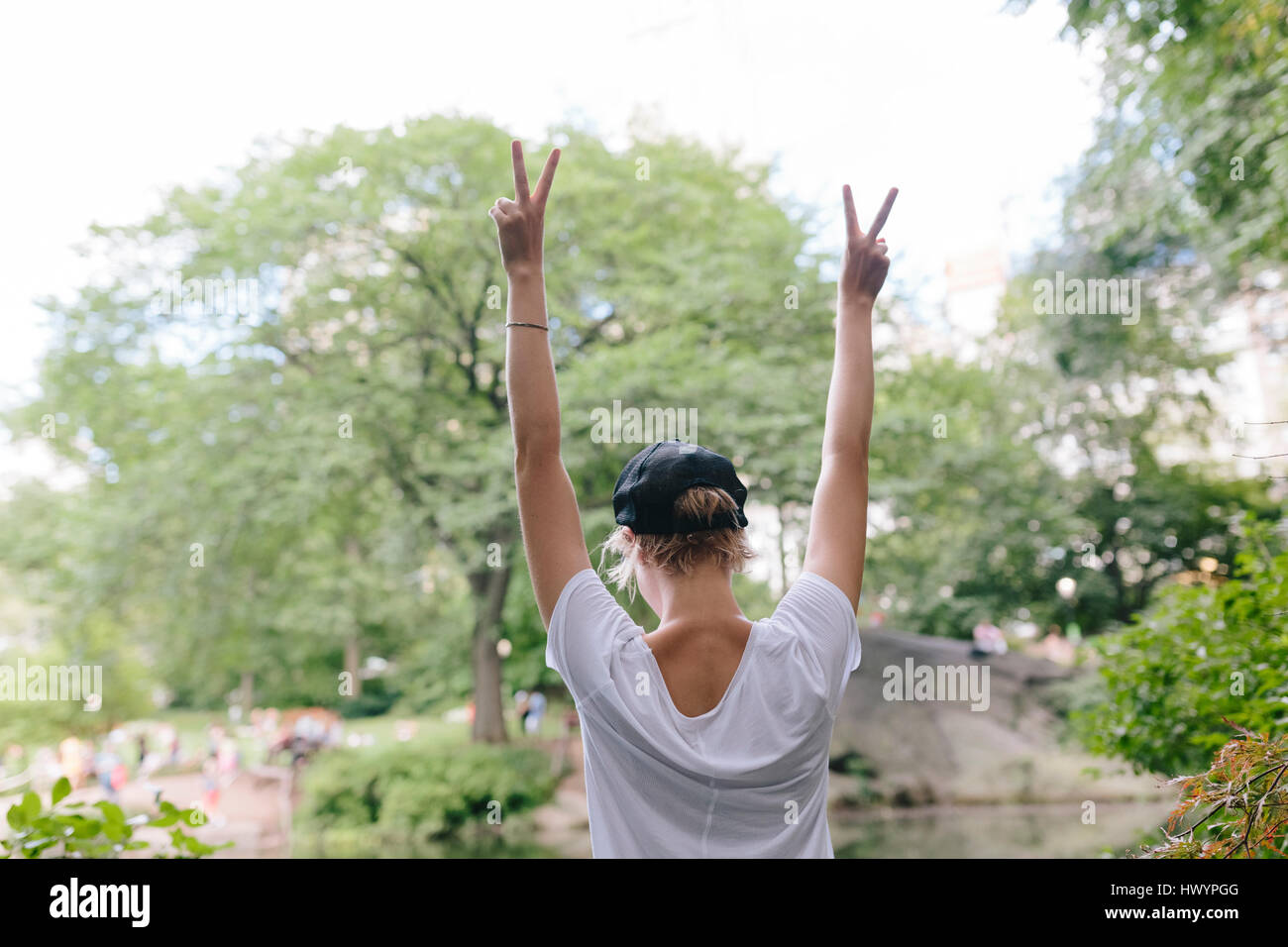 Rear view of young woman at lakeside in park with raised arms Stock ...