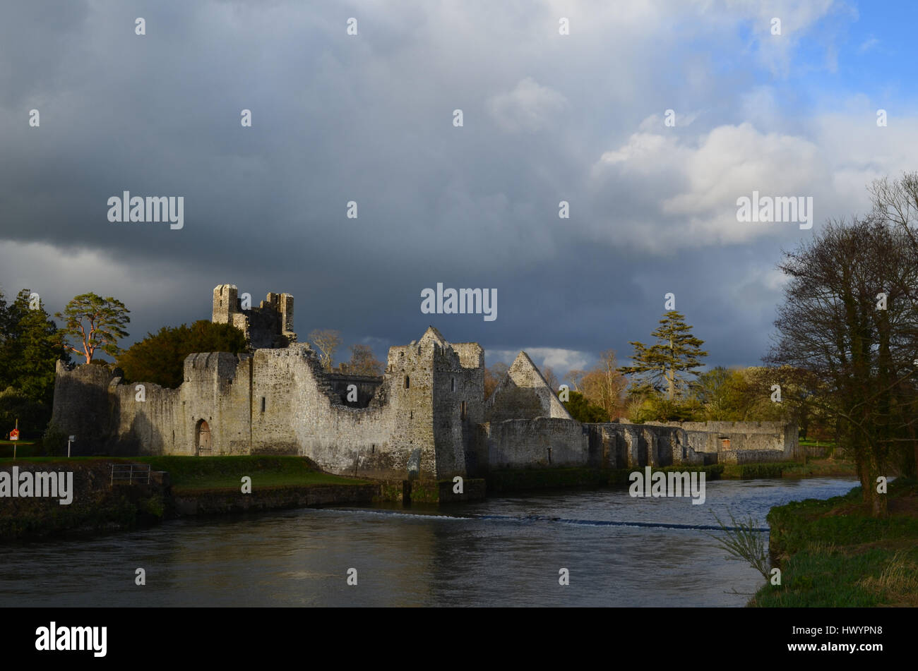 Desmond castle ruins with the sun shining through the clouds in Adare