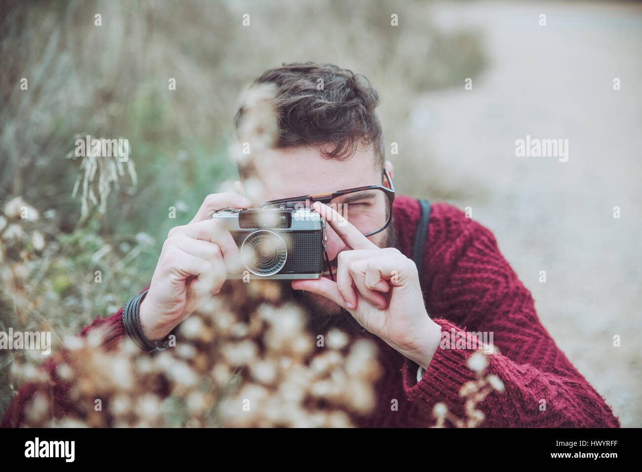 Bearded man taking photo of flowers with vintage camera Stock Photo