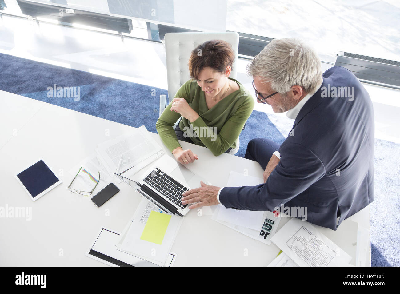 Businessman and businesswoman using laptop in office together Stock ...
