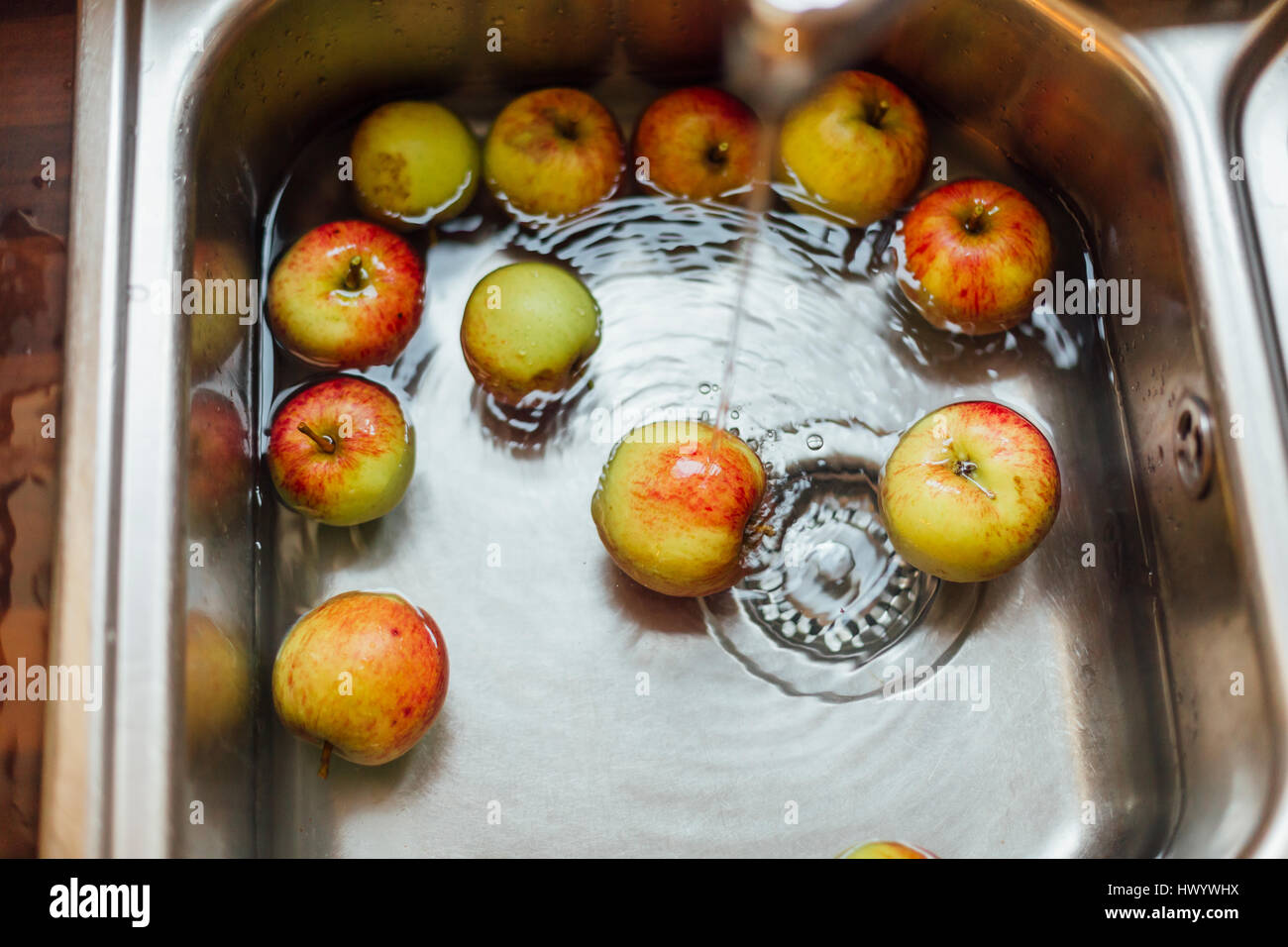 Washing apples in sink Stock Photo