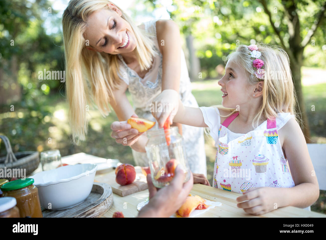 Smiling mother and daughter preserving peaches Stock Photo