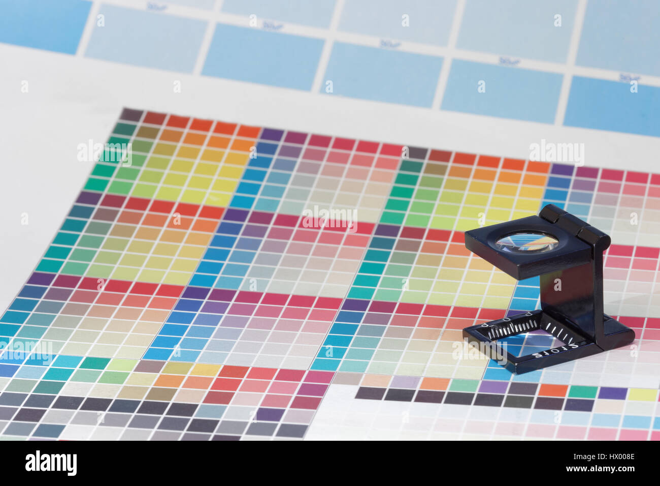 Magnifier or printer's loupe sits on a colorful CMYK test sheet in a pre-press workshop Stock Photo