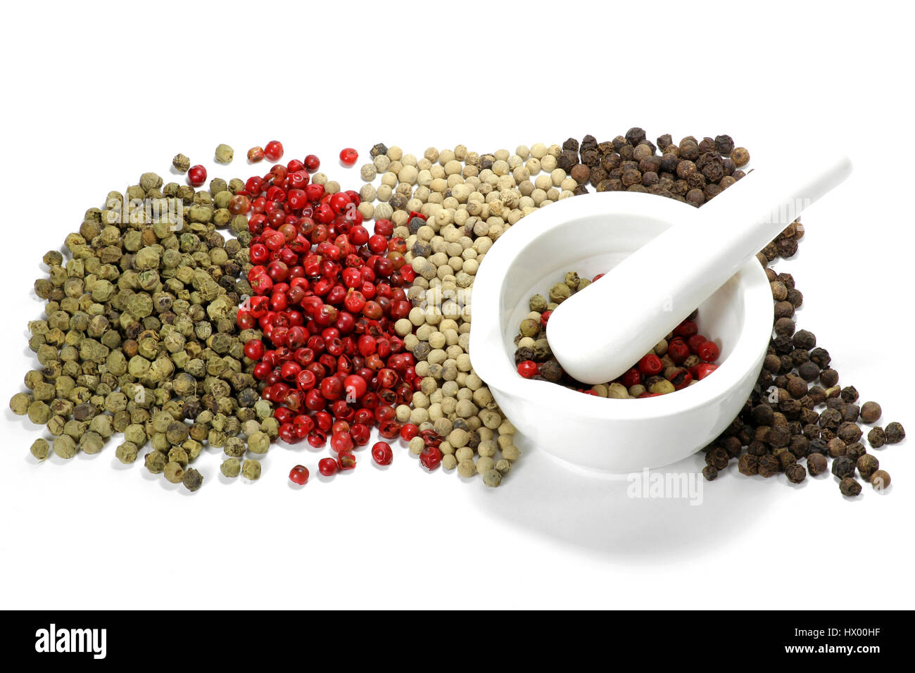 different colored peppercorns with a ceramic mortar isolated on white