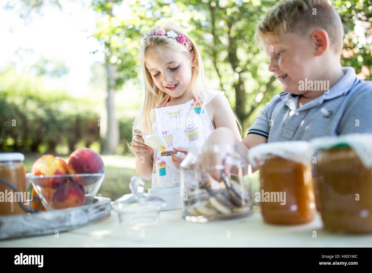 Smiling sister and brother at garden table Stock Photo - Alamy