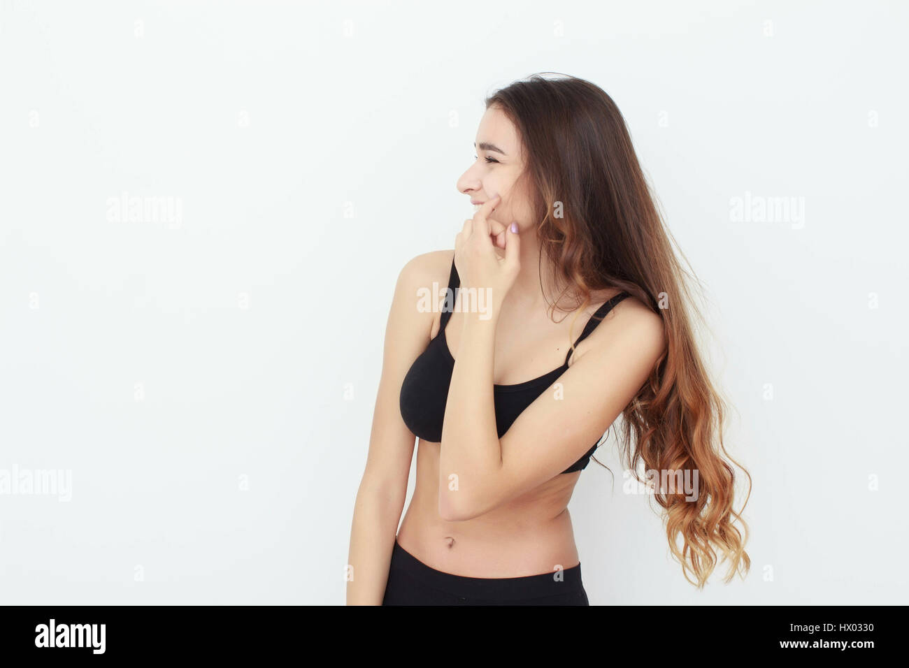 Beautiful girl in black top on white background shows emotion Stock Photo