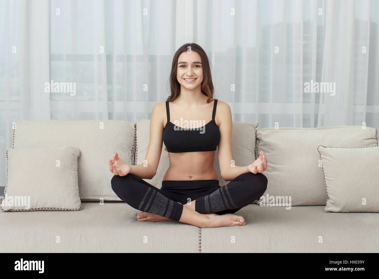 woman meditating in lotus position on the couch Stock Photo - Alamy