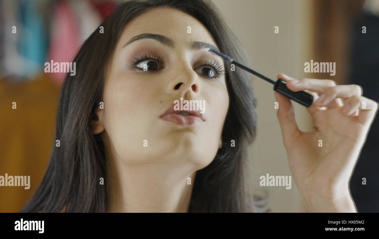 Low angle close up of concentrating woman applying mascara make-up Stock Photo