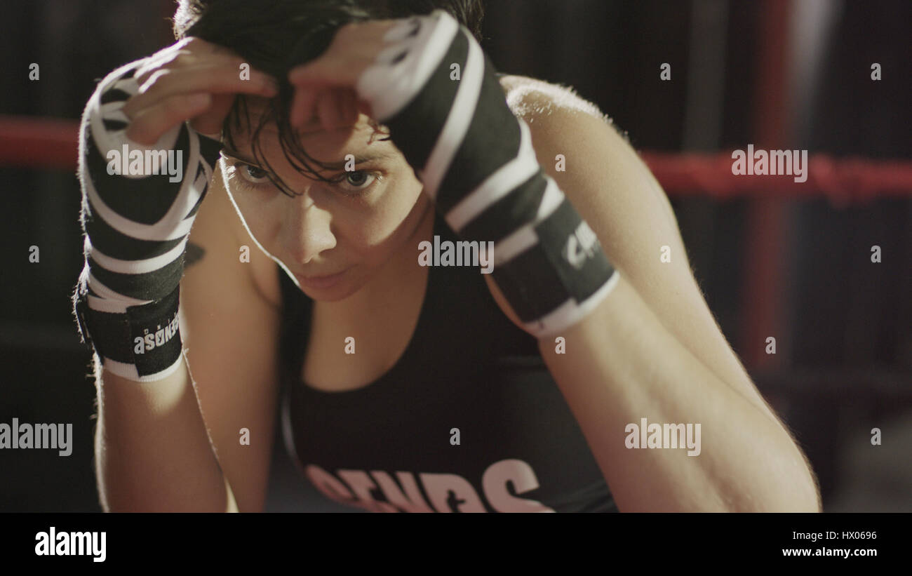 Close up of female boxer protecting her face standing in boxing ring during match Stock Photo
