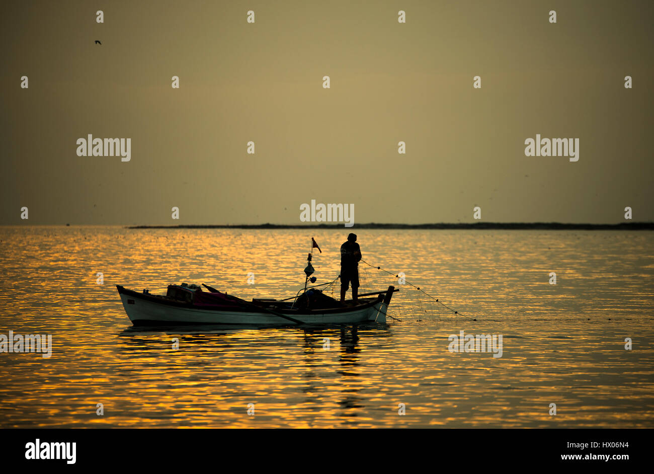 Fisherman on sunset with a boat and fishnet Stock Photo - Alamy