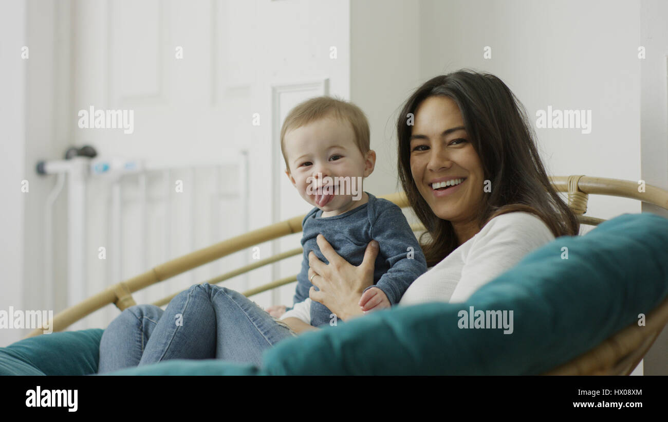 Low angle selective focus portrait of mother and baby son posing and sitting in chair Stock Photo