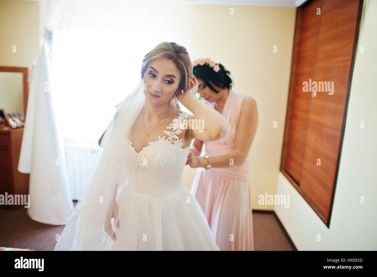 Fashionable Bridesmaids On Pink Dresses Helped Wear Bow On Back Of