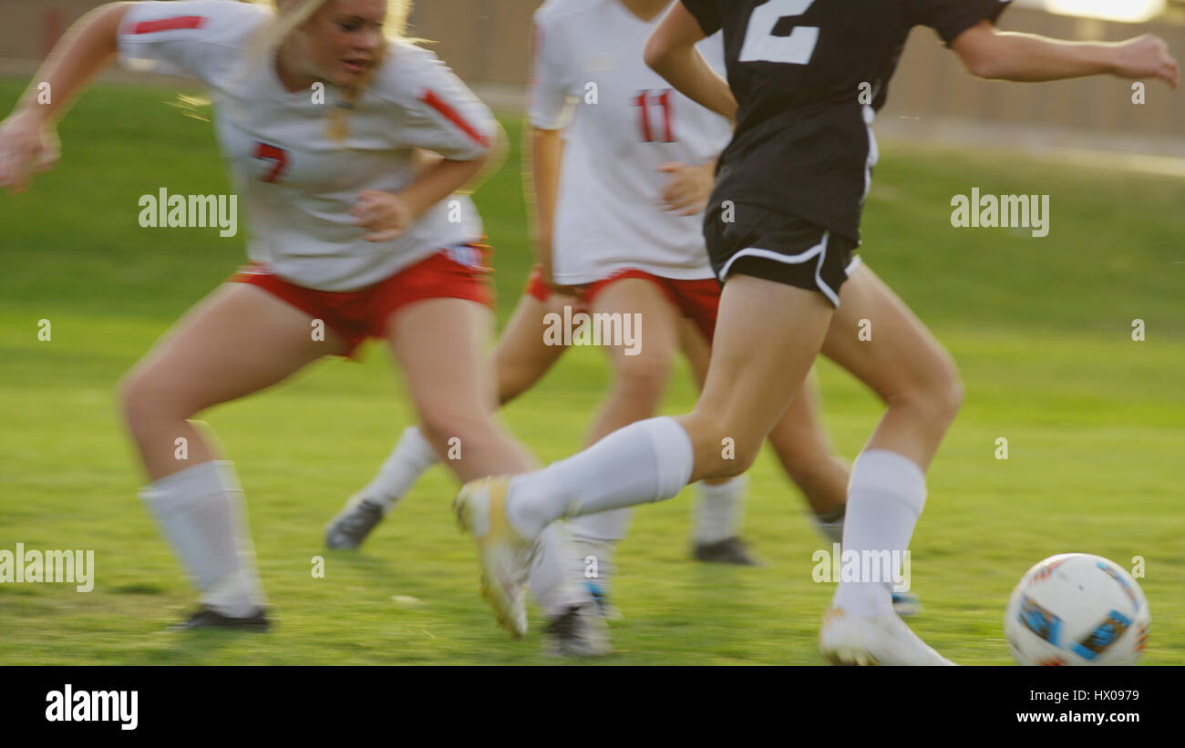 Blurred view of athlete with soccer teammates kicking ball on field Stock Photo