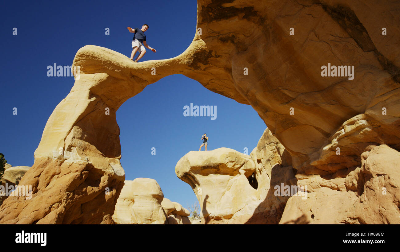 Low angle view of climbers balancing on scenic rock formations under clear blue sky Stock Photo