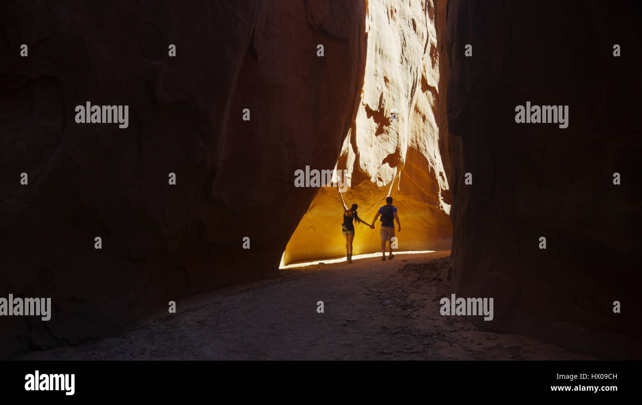 Rear view of silhouette of boyfriend and girlfriend exploring cave in scenic rock formations Stock Photo