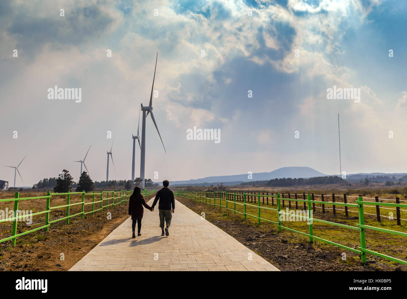 Lover hold hand at wind energy turbine farm, Jeju Island, South Korea Stock Photo