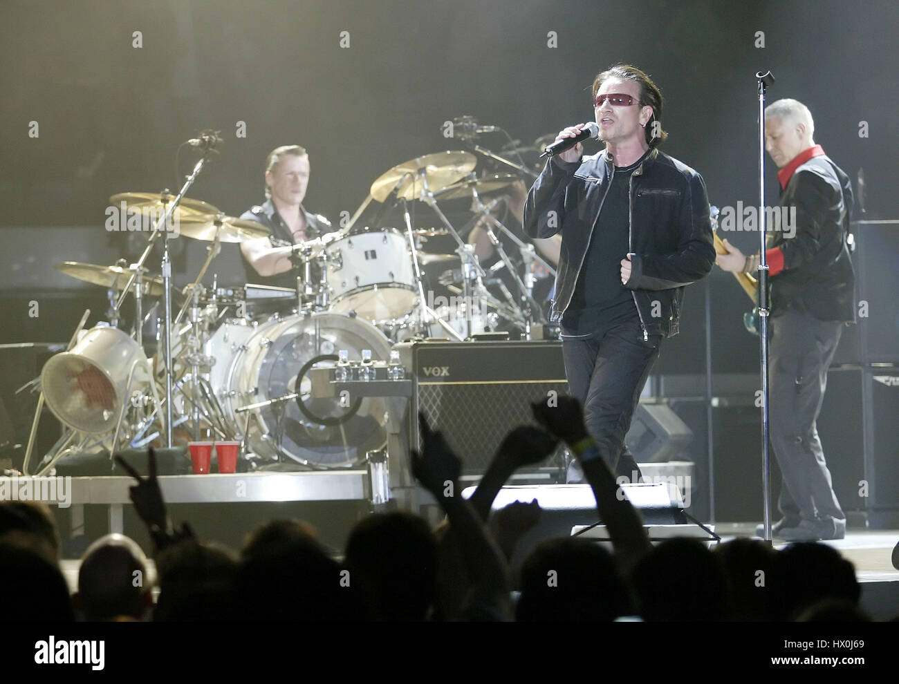 Lead singer of U2, Bono, in concert with drummer Larry Mullen and bass
