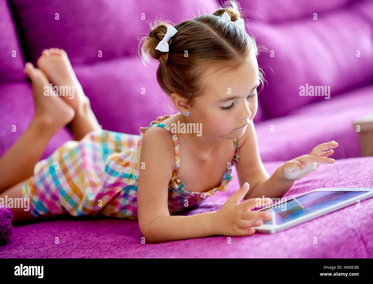 Little pretty girl with a tablet computer on a sofa at home Stock Photo ...