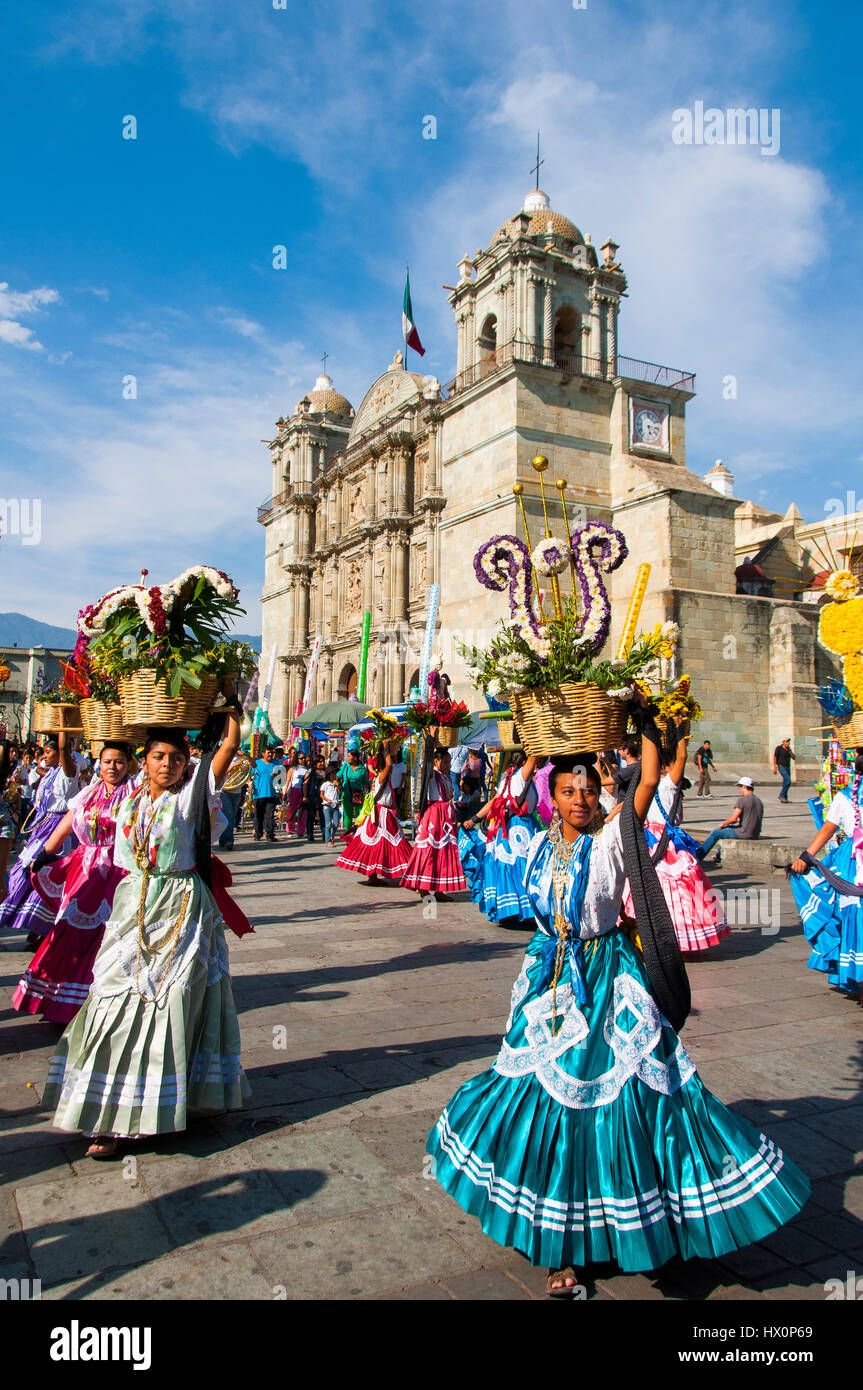 Women in traditional dresses with flower baskets dancing on the main square Zocalo in front of church Santo Domingo de Guzman Stock Photo