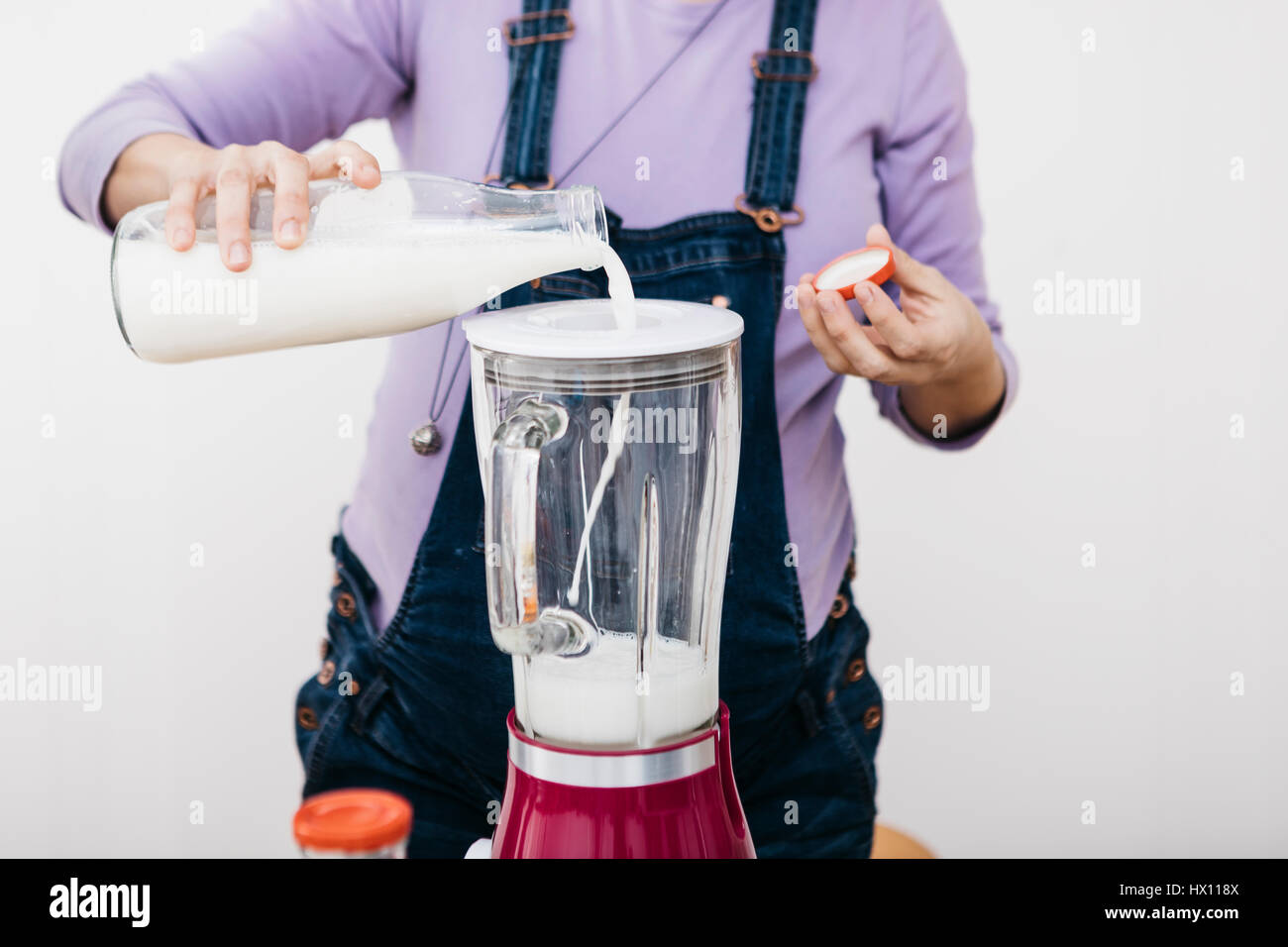 Pregnant woman pouring milk into a blender for preparing smoothie, partial  view Stock Photo - Alamy
