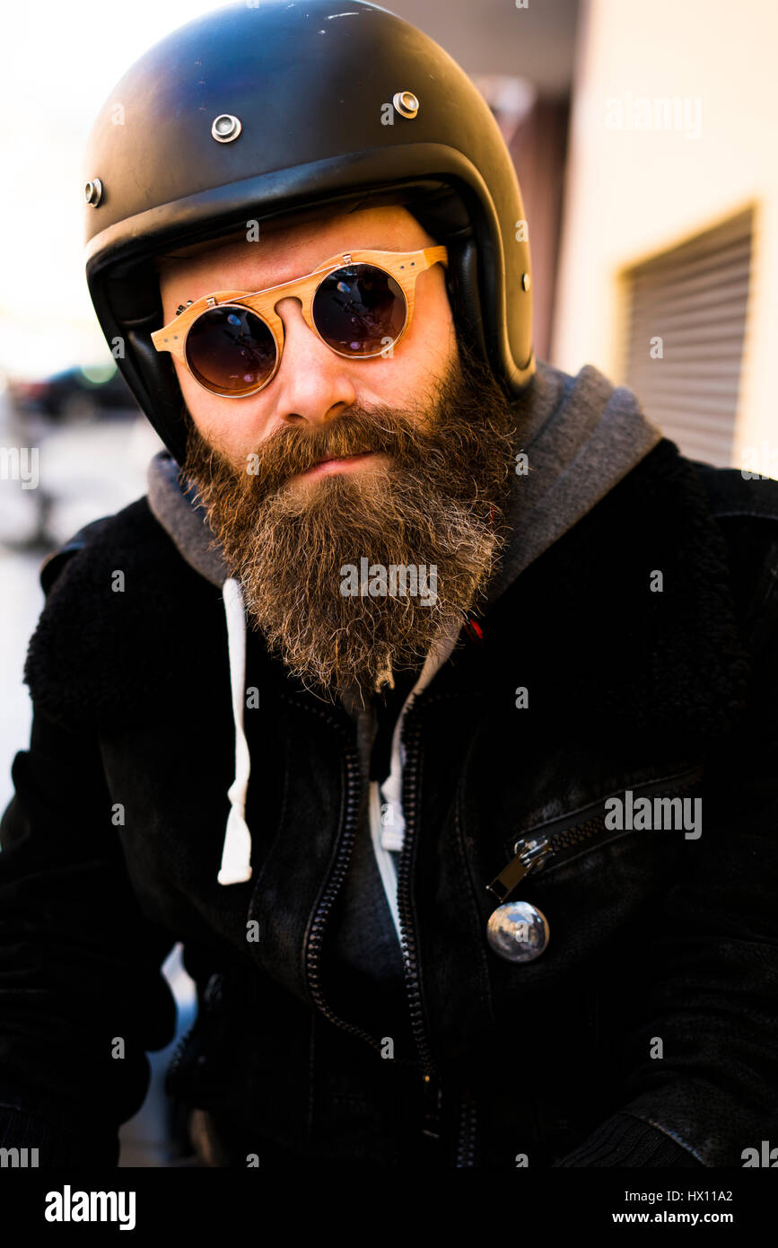 beard and motorcycle helmet Portrait of bearded biker wearing helmet and sunglasses Stock Photo