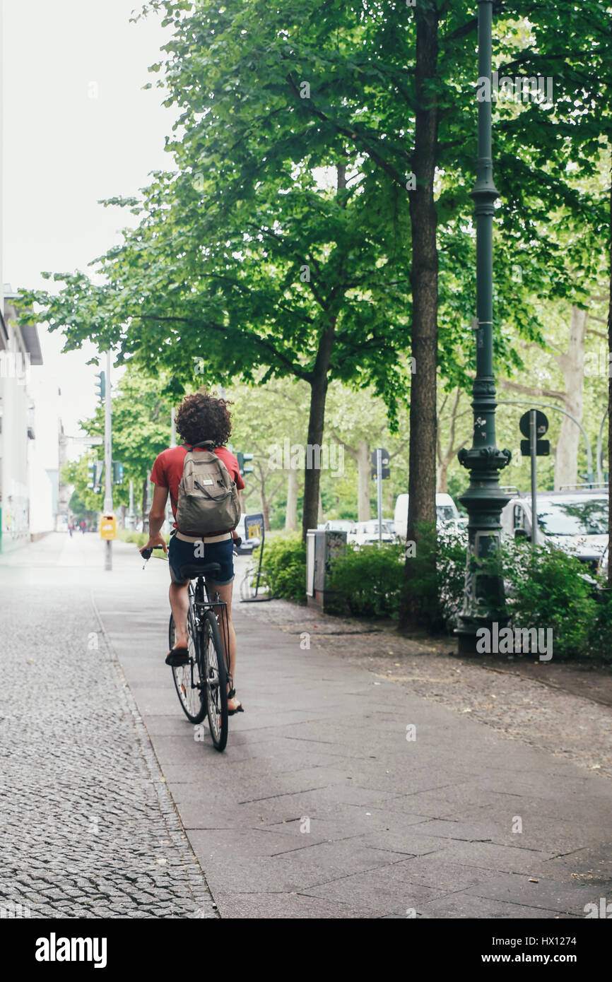 Young man riding bicycle on pavement Stock Photo - Alamy