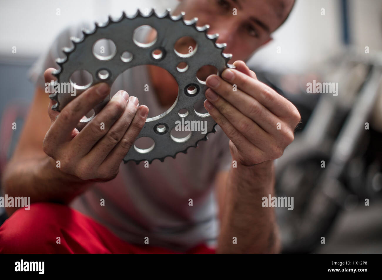Mechanic in workshop holding a sprocket Stock Photo